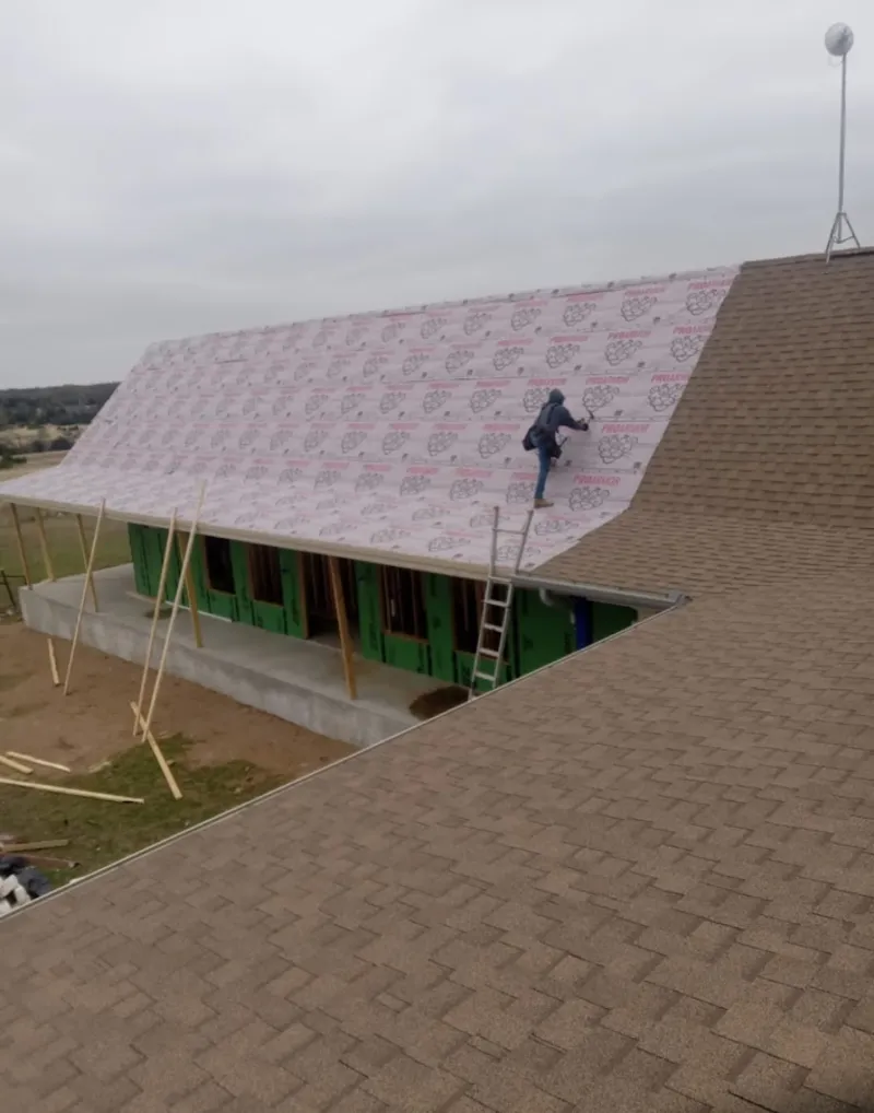 Worker preparing underlayment for a metal roof installation in Lovington
